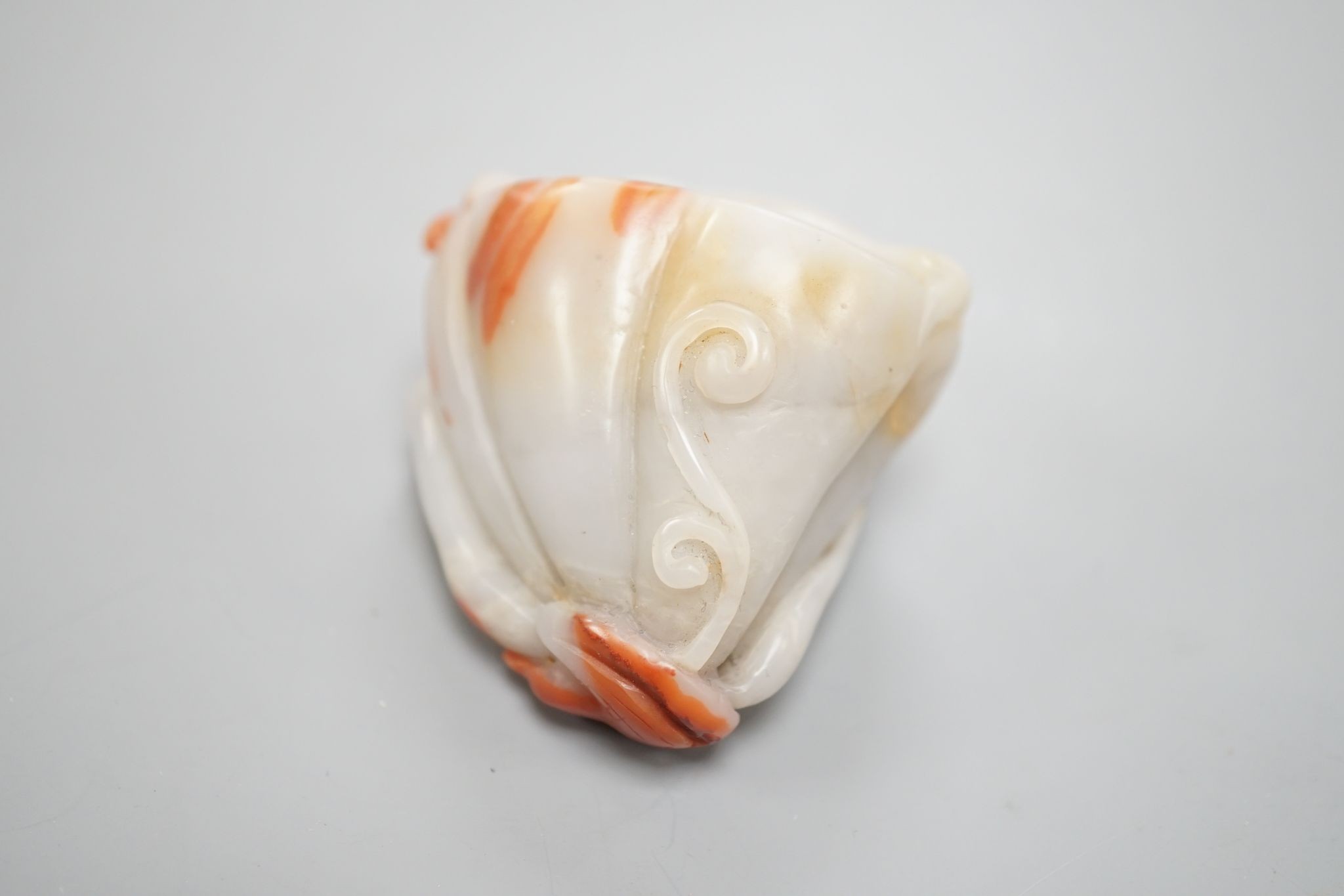 A Chinese pale celadon and russet jade 'lotus pod and fish' carving 6cm